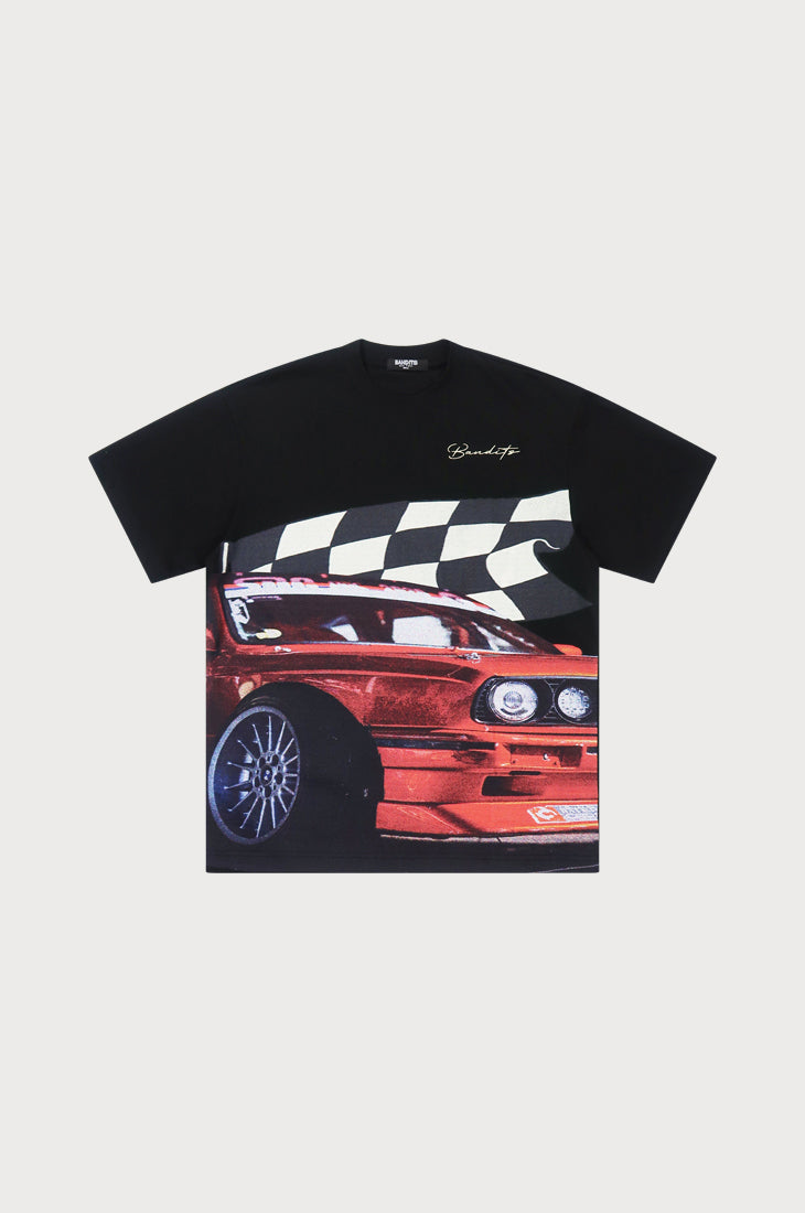 The BBS S/S TEE BLACK is an oversized embroidered black t-shirt made from heavy GSM cotton, showcasing a large DTG-printed red sports car graphic with bold white stripes and a cursive signature near the neckline.